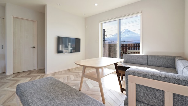 A modern living room with a sofa, a small table, and a TV mounted on the wall. - Mt Fuji Resort Club -Relax- (Fujikawaguchiko)