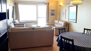 Uma sala de estar moderna com um sofá, uma mesa de jantar e uma televisão.