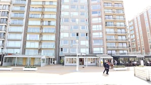 Um edifício residencial com vários andares, varandas, área de estar coberta e um restaurante chamado "Principal".
