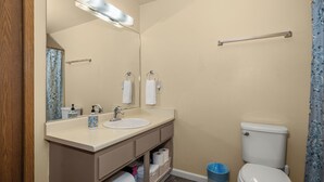 A bathroom with a sink, mirror, toilet, and a trash bin. - Beautiful 2BR APT 2 ⭑ Netflix & Keurig ⭑ Full Kitchen ⭑ WiFi ⭑ AC (Spokane Valley)