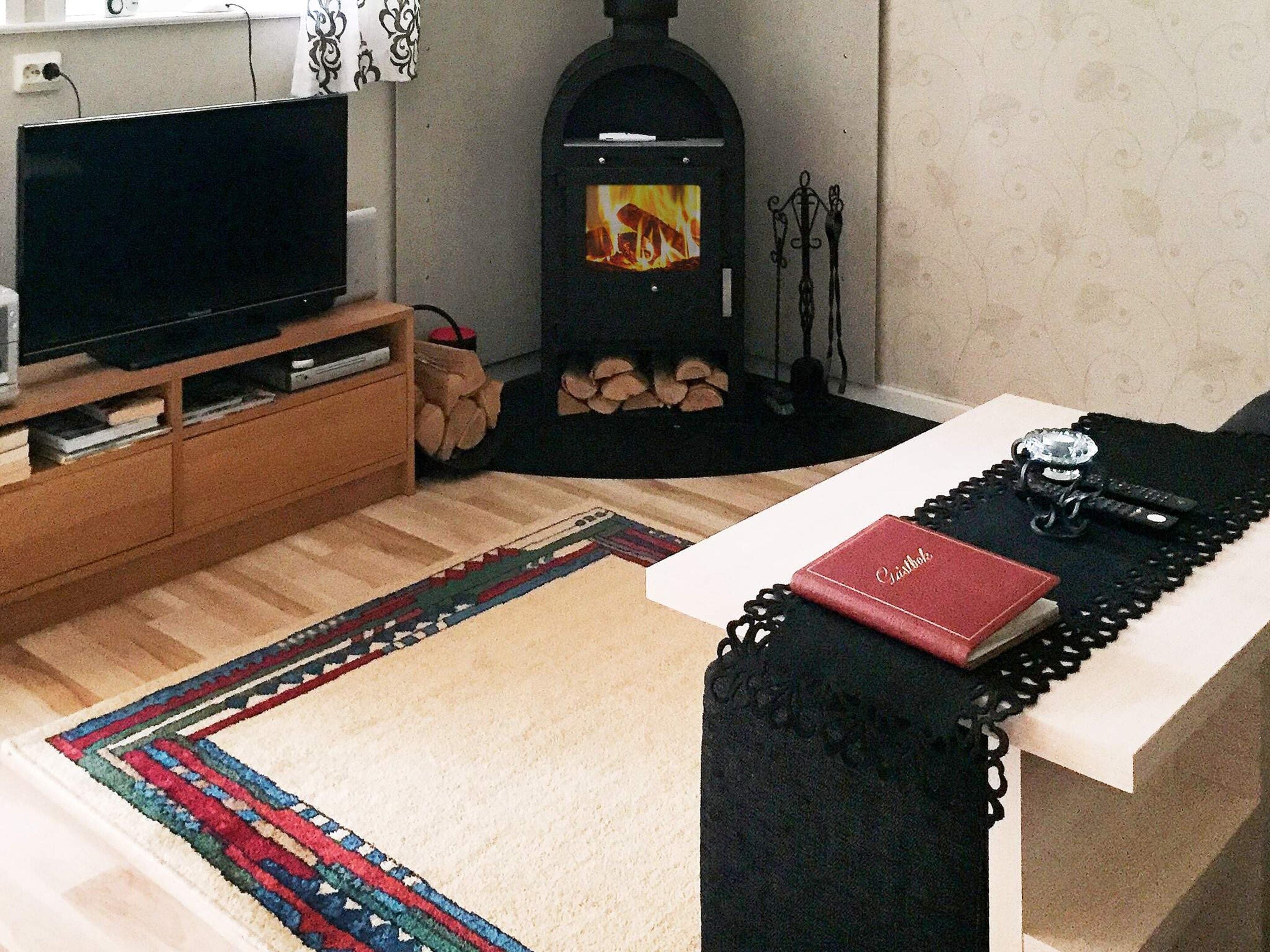 A living room with a television, a fireplace, a sofa, and a table with a book and a ring.