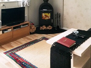 A living room with a television, a fireplace, a sofa, and a table with a book and a ring. - 4 Star Holiday Home in Gotlands Tofta (Gotlands Tofta)