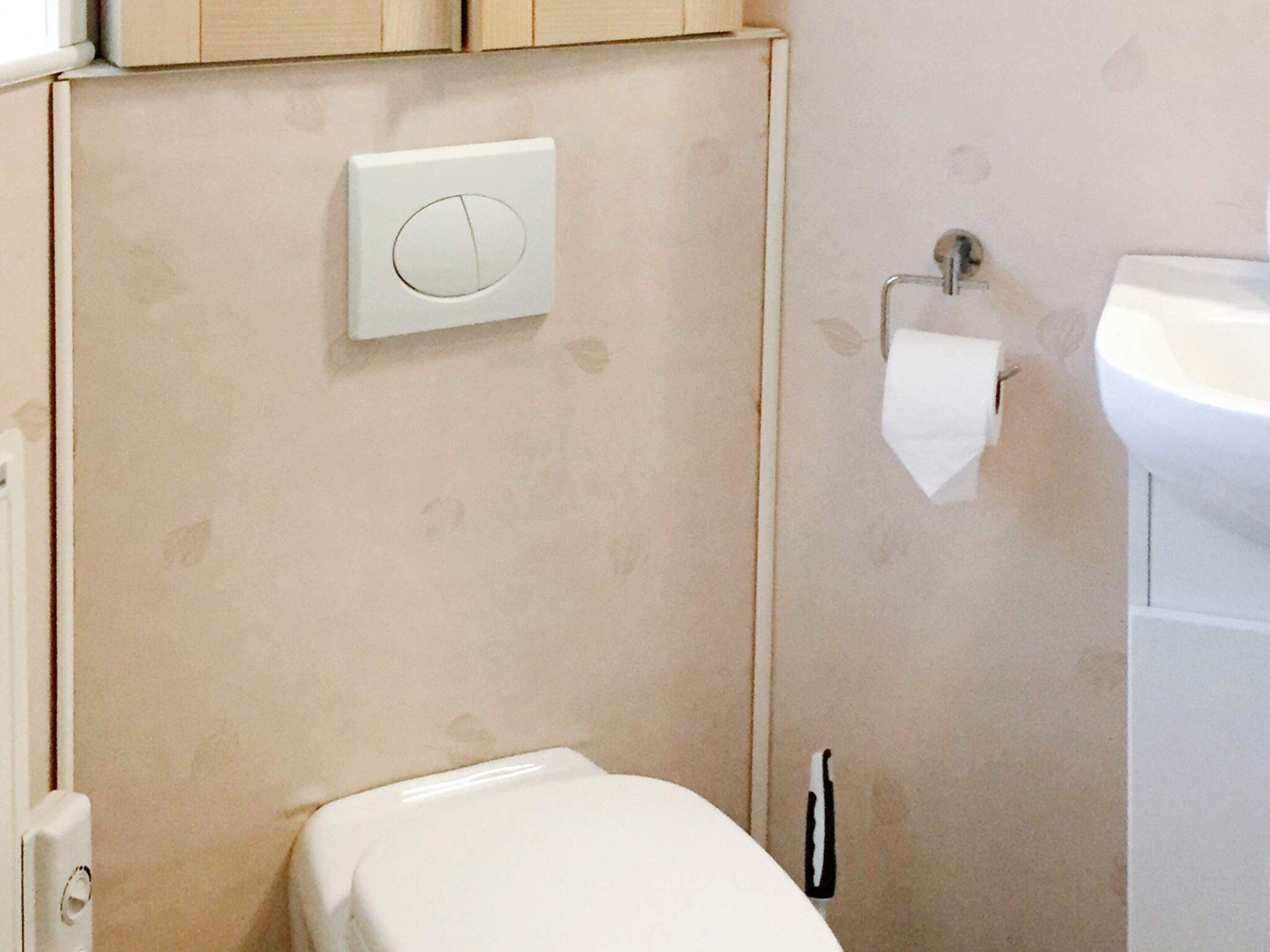 Ein Badezimmer mit Toilette, Waschbecken und Papierhandtuchhalter.