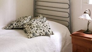 A bed with a metal headboard, two patterned pillows, and a bedside lamp on a wooden nightstand. - 4 Star Holiday Home in Gotlands Tofta (Gotlands Tofta)