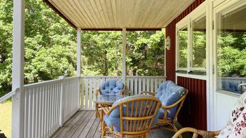 A covered porch with wicker furniture and a glass table.