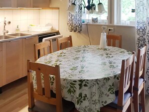 A dining area with a round table covered by a floral tablecloth, surrounded by wooden chairs. - 4 Star Holiday Home in Gotlands Tofta (Gotlands Tofta)