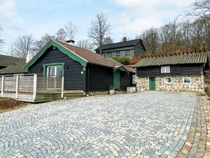 A traditional wooden building with a green door and a stone wall adjacent to it. - 4 Star Holiday Home in Bastad (Bastad)