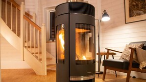 A modern living room with a wood-burning stove, a staircase, and a cozy seating area. - Kugelhaus Phoebe (Penzlin)