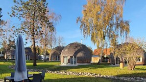 A residential area with dome-shaped houses, a grassy lawn, and a dining area with outdoor furniture. - Kugelhaus Phoebe (Penzlin)