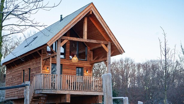 A wooden cabin with a balcony, a staircase, and a sign reading "Eekhoorn".