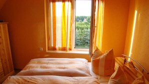 Un dormitorio con dos camas, una ventana con cortinas y vistas a zonas verdes.