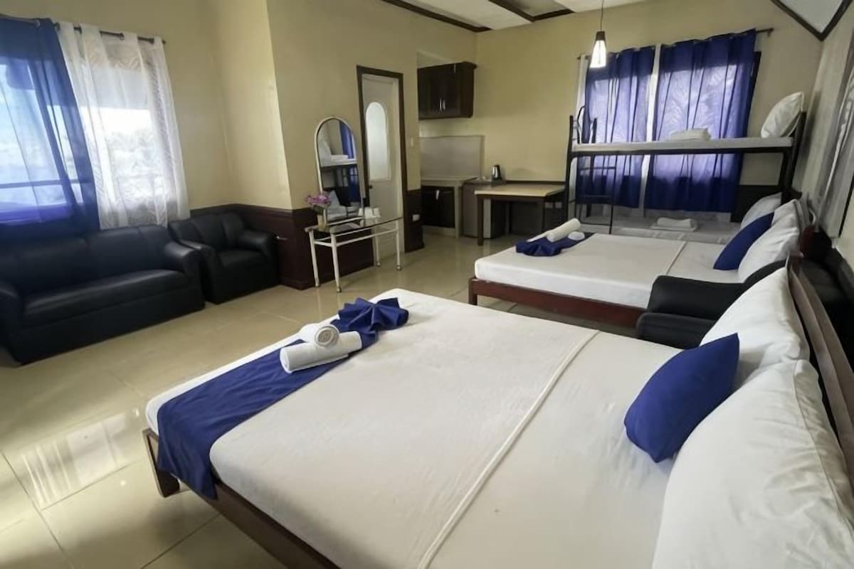 A hotel room with two beds, a sofa, a desk, and a mirror.