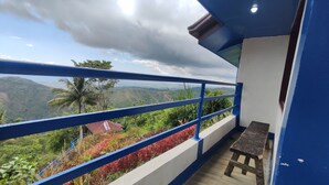 A balcony with a blue railing overlooking a lush landscape with hills and a palm tree. - JVR Island in the Sky Resort (Balamban)