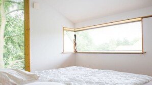 A bedroom with a bed, a window, and a view of trees. - Huis aan het Park (Bispingen)