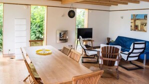 A spacious room with a wooden dining table, chairs, a sofa, and a television. - Huis aan het Park (Bispingen)