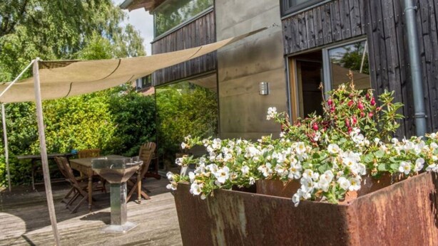 A modern house with a deck, a pergola, and a flower planter. - Huis aan het Park (Bispingen)