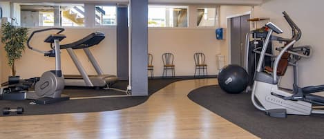 A gym with exercise equipment, a treadmill, a stationary bike, and a rowing machine.