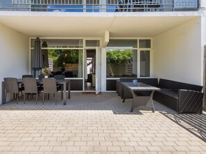 An outdoor patio with a dining table and chairs, a sofa, and a covered seating area.