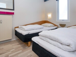 A hotel room with two beds, a radiator, a window, and a mirror.