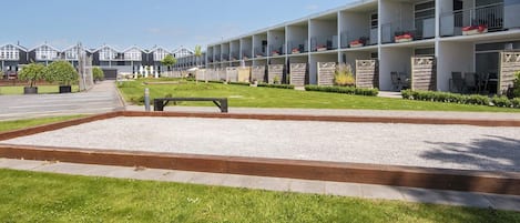 A modern hotel with a row of balconies, a well-maintained lawn, and a gravel pathway.