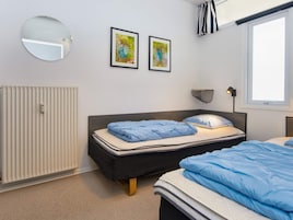 Un dormitorio con cama, radiador, ventana y dos cuadros en la pared.