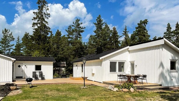 A row of white cabins with a grassy yard and trees in the background. - 4 Star Holiday Home in Monsteras (Monsteras)