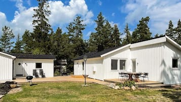 A row of white cabins with a grassy yard and trees in the background.