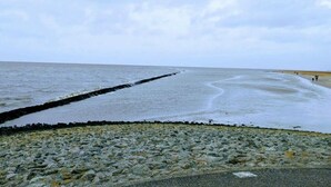 A rocky beach with a jetty extending into the sea. - Huus Meta Modern Retreat (Krummhoern)