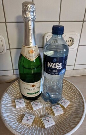A bottle of Stolzenfels Trocken and a bottle of Vilsal Classic water on a tray with chocolate boxes. - Huus Meta Modern Retreat (Krummhoern)