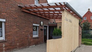 A brick building with a wooden reception desk and a clock above the door. - Huus Meta Modern Retreat (Krummhoern)