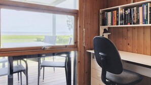 A room with a wooden desk, a chair, a bookshelf, and a window overlooking a deck. - 4 Star Holiday Home in Praesto (Praesto)