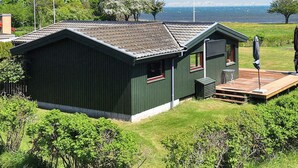 A small, single-story building with a sloped roof, a deck, and a view of the sea. - 4 Star Holiday Home in Praesto (Praesto)