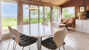 A spacious room with a large dining table, comfortable seating, a television, and a view of the outdoors. - 4 Star Holiday Home in Praesto (Praesto)