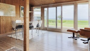 A spacious room with wooden walls and a large window offering a view of the sea. - 4 Star Holiday Home in Praesto (Praesto)