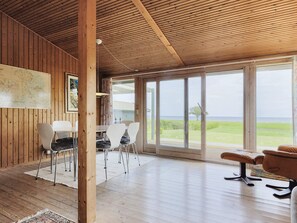Una habitación amplia con paredes de madera y un ventanal que ofrece vistas al mar.