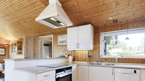 A modern kitchen with white cabinetry, a built-in oven, and a window providing natural light. - 4 Star Holiday Home in Praesto (Praesto)