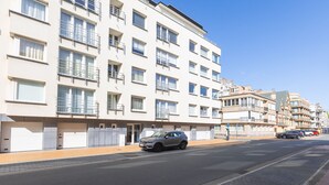 A multi-story residential building with balconies, a paved street, and parked cars. - Distellaan 72 Dune Retreat (Middelkerke)