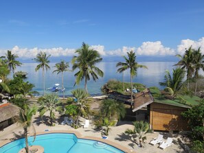 A resort with a swimming pool, palm trees, and a view of the ocean. - The Wild Orchid Resort - Moalboal (Moalboal)