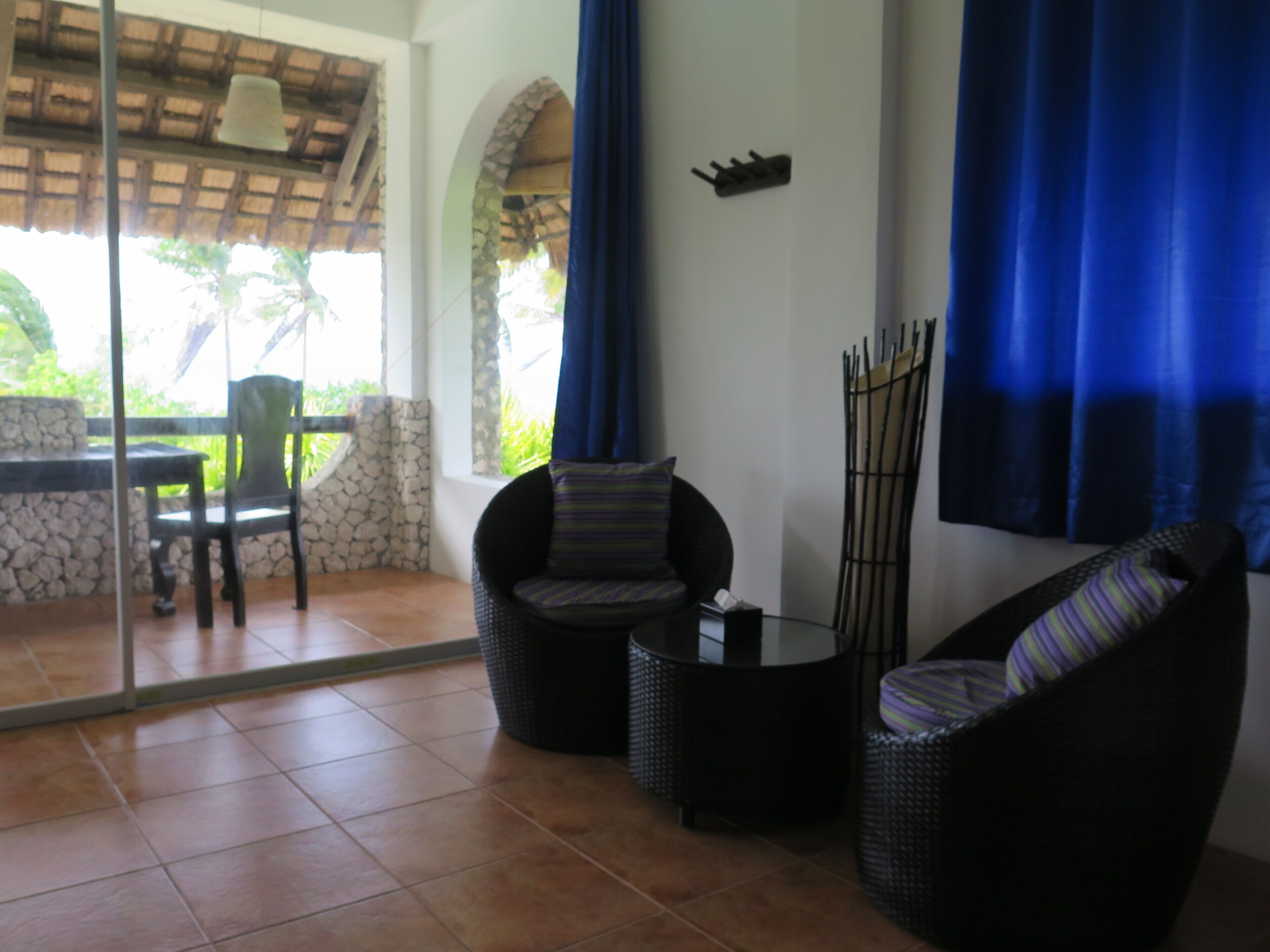 A patio area with wicker furniture, a stone wall, and a glass door leading to an outdoor space.