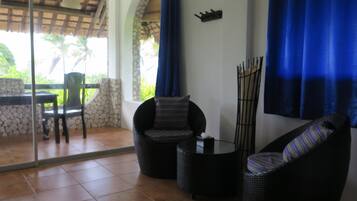 A patio area with wicker furniture, a stone wall, and a glass door leading to an outdoor space.