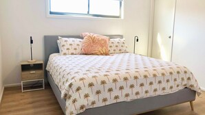 A bedroom with a bed, nightstand, and a window.