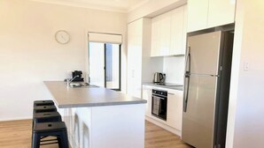 A modern kitchen with a central island, stainless steel appliances, and a wooden floor.