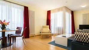Una sala de estar moderna con un sofá, una mesa de centro, un televisor y un comedor con sillas y una mesa.