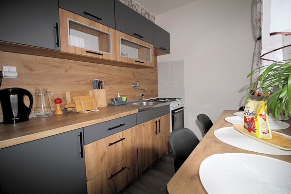 Een moderne keuken met houten kastjes, een gasfornuis en een eethoek met een tafel en stoelen.