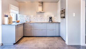 Cozinha moderna com armários cinza, backsplash estampado e forno embutido.