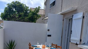 Un tavolo rotondo con sedie e un vaso di fiori su un patio piastrellato.