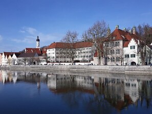 A historic building with a prominent tower and a reflection in the water. - Schleichhof Ammersee (Dießen am Ammersee)
