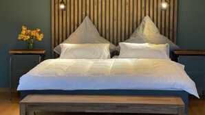 A bed with white linens, two pillows, and a wooden headboard with vertical slats.