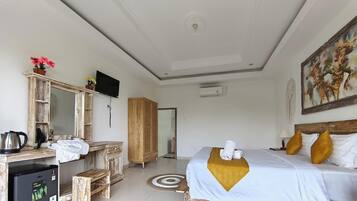 Habitación de hotel con cama, escritorio con cafetera, armario, televisor y un cuadro en la pared.