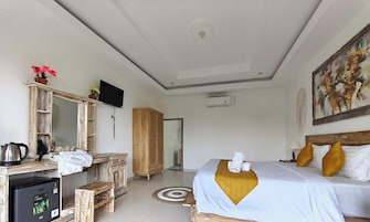 Habitación de hotel con cama, escritorio con cafetera, armario, televisor y un cuadro en la pared.